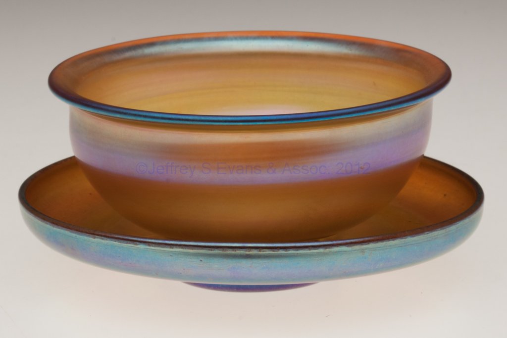 TIFFANY FAVRILE FINGER BOWL AND UNDERPLATE: TIFFANY FAVRILE FINGER BOWL AND UNDERPLATE, gold iridescent, each signed "L.C.T. Favrile" and with polished pontil mark. Louis Comfort Tiffany & Co. First quarter 20th century. 2 1/4" HOA, 4 5/8" and 