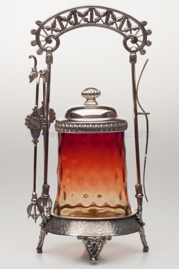 OVAL SPOT-OPTIC PICKLE CASTER: OVAL SPOT-OPTIC PICKLE CASTER, Rose Amber/amberina, polished pontil mark, Rogers Smith & Co., Meriden quadruple-plate stand with tongs and fork. Probably Mt. Washington Glass Co. Fourth quarter 19th c