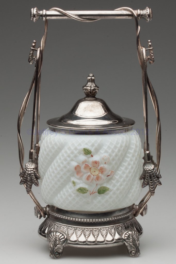 APPLE BLOSSOM PICKLE CASTER: APPLE BLOSSOM PICKLE CASTER, opaque white with enamel decoration, Rogers & Bro. #4663 quadruple-plate stand with two tongs. Northwood Glass Co. Late 19th/early 20th century. 9 3/4" HOA, 3 1/2" H jar. 