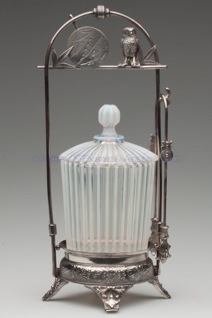 BEATTY RIB PICKLE CASTER: BEATTY RIB PICKLE CASTER, colorless opalescent, matching glass cover, Derby #179 quadruple-plate stand with owl and fan in handle, with tongs. Beatty & Sons, Tiffin, OH. Fourth quarter 19th century. 1