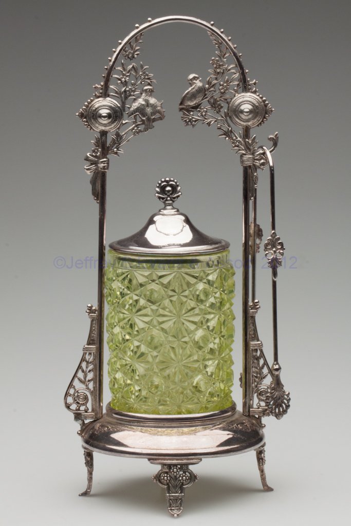 EAPG DAISY AND BUTTON PICKLE CASTER: EAPG DAISY AND BUTTON PICKLE CASTER, vaseline (uranium), Meriden #195 quadruple-plate stand with tongs. Fourth quarter 19th century. 12 3/4" HOA, 4 1/4" H jar. Provenance: From the collection of the l