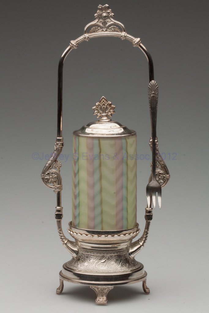 MOTHER-OF-PEARL SATIN PICKLE CASTER: MOTHER-OF-PEARL SATIN PICKLE CASTER, opal cased rainbow with herringbone air traps, small ground pontil mark, Wilcox #1247 quadruple-plate stand with fork. Stand fourth quarter 19th century. Jar 20th 