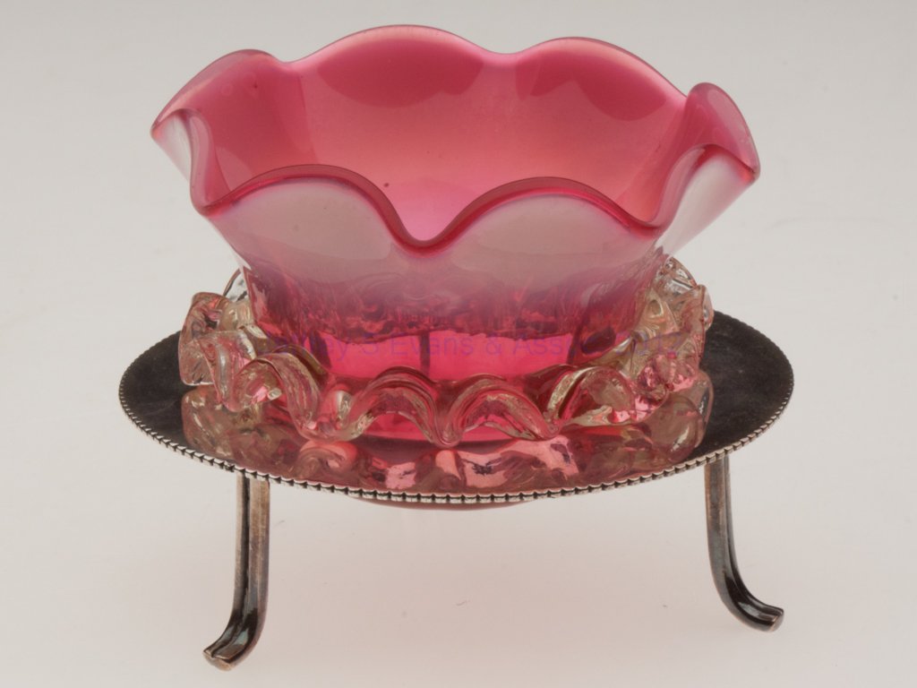 RIB-OPTIC OPEN SALT: RIB-OPTIC OPEN SALT, cranberry opalescent with applied pale vaseline (uranium) rigaree, polished pontil mark, fitted in a "GP&S / EP" stand with three feet. Late 19th/early 20th century. 2 1/2" H, 2 5