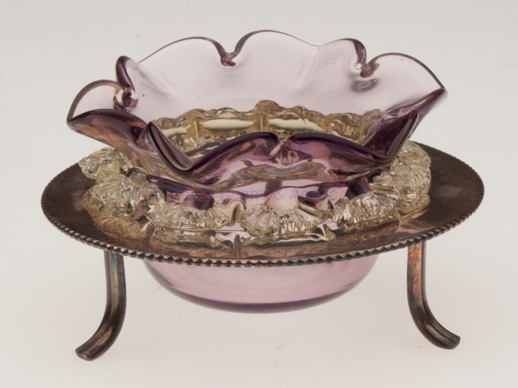 UNPATTERNED OPEN SALT: UNPATTERNED OPEN SALT, amethyst with applied vaseline (uranium) rigaree, six-petal rim, polished pontil mark, fitted in a "D&A" silver-plated frame with three feet. Late 19th/early 20th century. 1 3/4