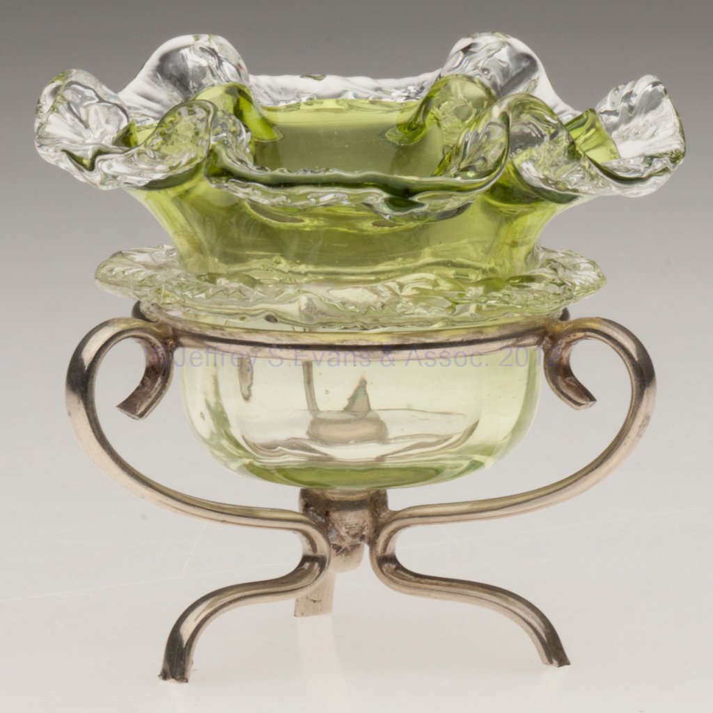 RIB-OPTIC OPEN SALT: RIB-OPTIC OPEN SALT, shaded yellow green with an applied colorless rim and rigaree, polished pontil mark, fitted in an "EPNS" stand with three feet. Late 19th/early 20th century. 2 3/4" H, 3" D rim. L