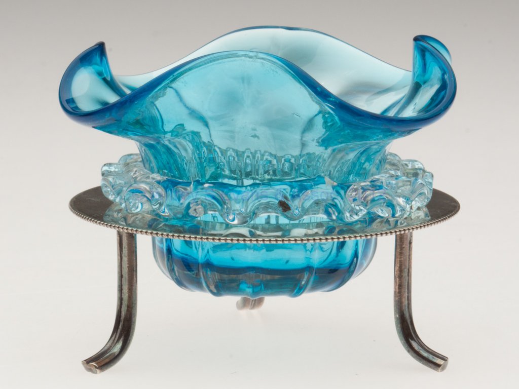 RIB-OPTIC OPEN SALT: RIB-OPTIC OPEN SALT, blue with applied colorless rigaree, polished pontil mark, fitted in a "D&A / EPNS" stand with three feet. Late 19th/early 20th century. 2 1/2" H, 3 3/8" D rim. Provenance: From t