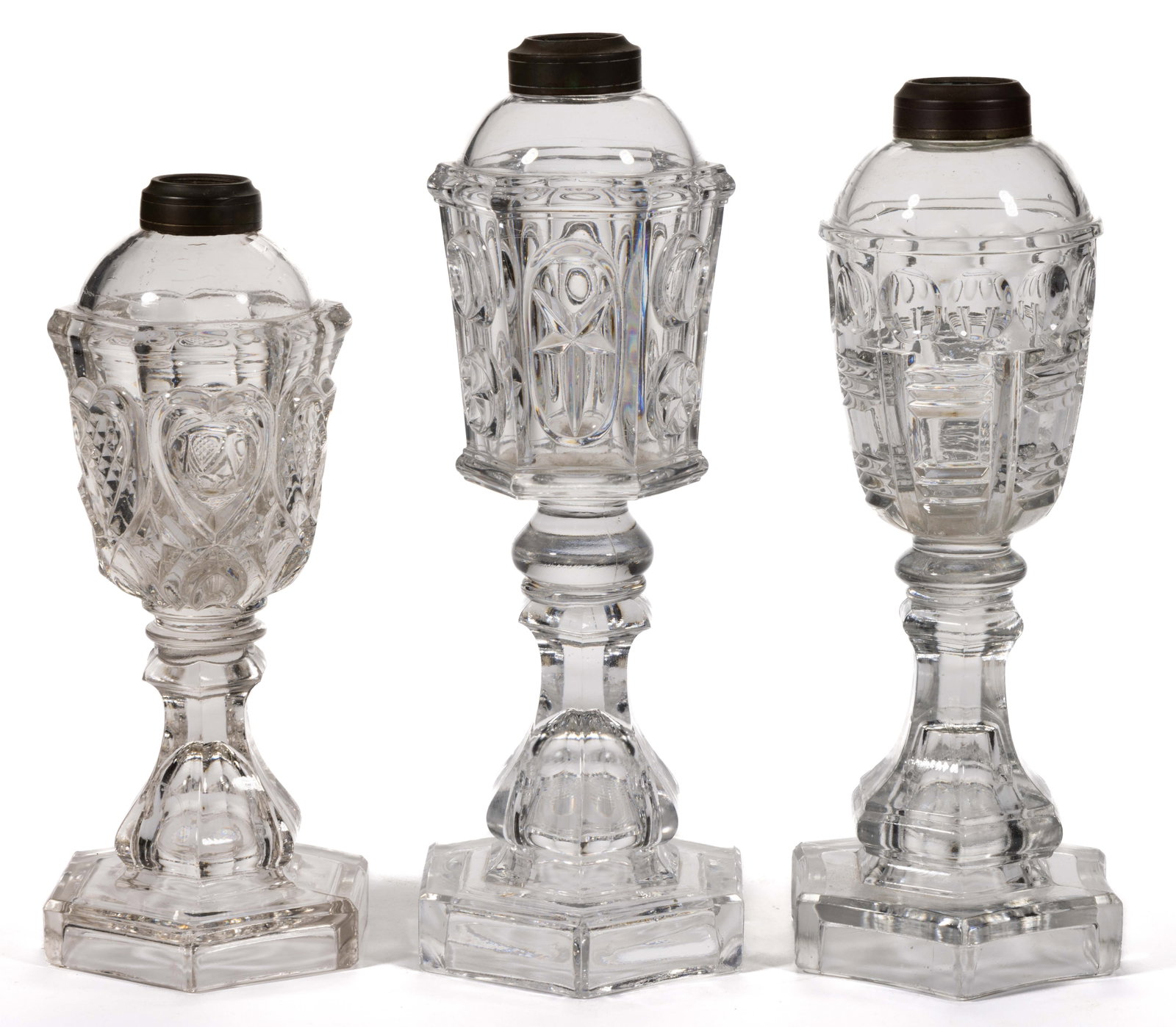 ASSORTED PRESSED PATTERN FLUID / WHALE OIL STAND LAMPS, LOT OF THREE: ASSORTED PRESSED PATTERN FLUID / WHALE OIL STAND LAMPS, LOT OF THREE, colorless, comprising a Heart, a Prism and Crescent, and a Star and Punty; each with a hexagonal stem and foot, period No. 1 and N