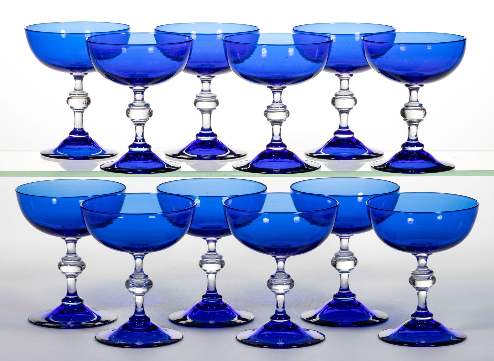 STEUBEN NO. 6869 ART GLASS CHAMPAGNES, SET OF 12: STEUBEN NO. 6869 ART GLASS CHAMPAGNES, SET OF 12, Flemish Blue with colorless stems, polished pontil marks. Each with an acid-stamped signature. Steuben Glass Works. Circa 1925. 5" H. Proven