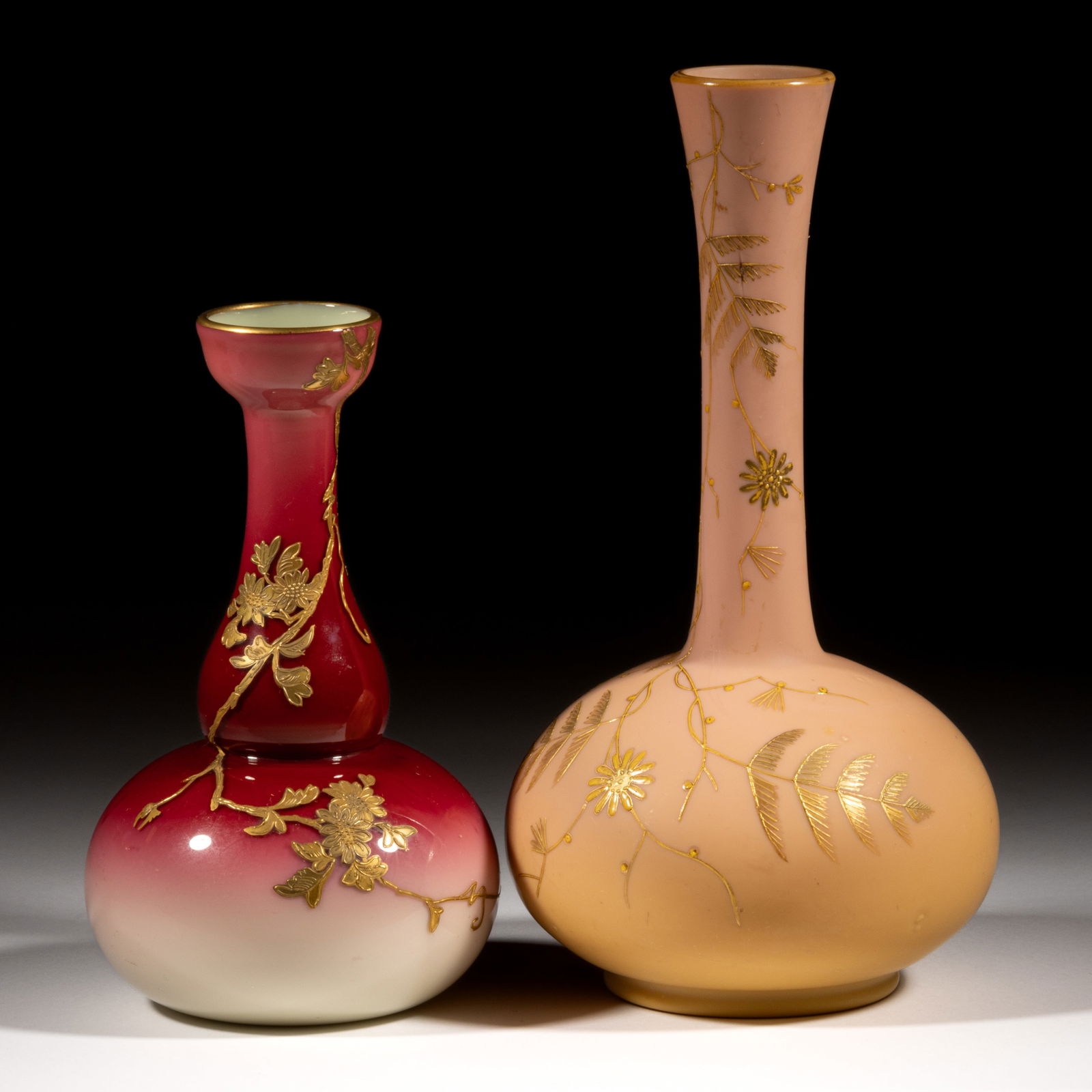 WEBB GILT-DECORATED GLASS VASES, LOT OF TWO: WEBB GILT-DECORATED GLASS VASES, LOT OF TWO, comprising a Burmese-type bud vase, and a Peachblow-type gourd form, each having gilt flowering branch decoration. Thomas Webb & Sons. Fourth quarter 1