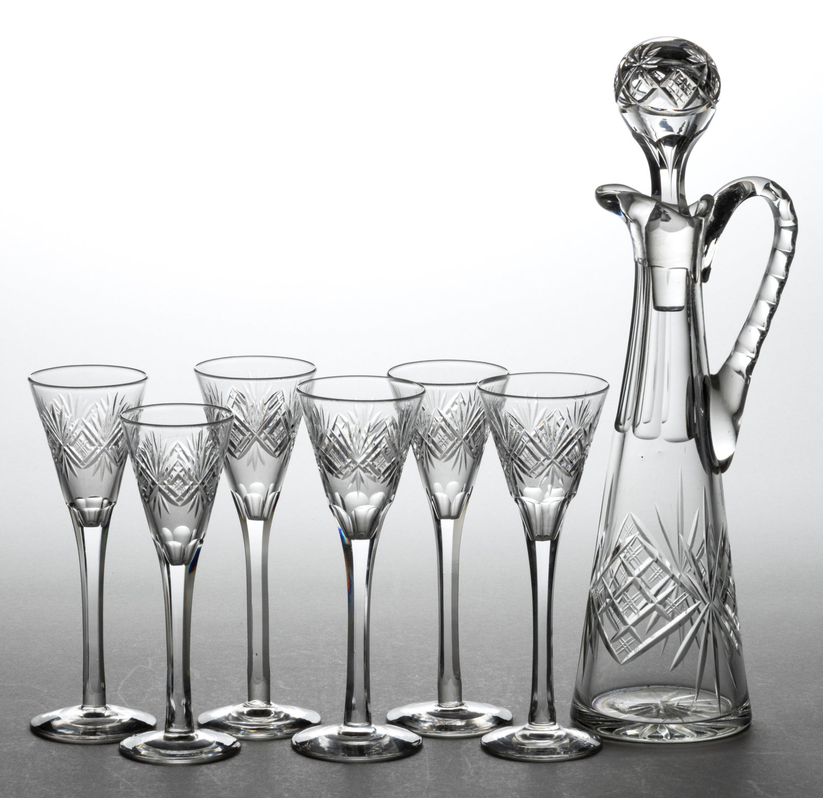 CUT GLASS CORDIAL / WINE DRINKING ARTICLES, SET OF SEVEN: CUT GLASS CORDIAL / WINE DRINKING ARTICLES, SET OF SEVEN, colorless, comprising a tall conical ewer-form decanter with matching stopper, applied handle, and tooled spout; and a matching set 