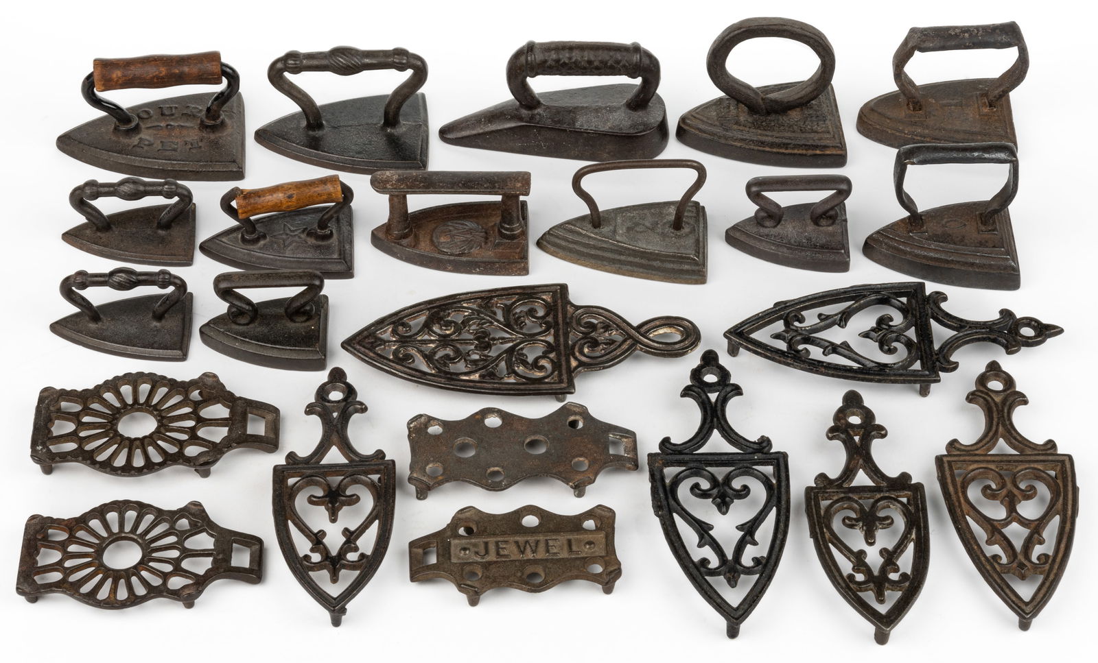 ASSORTED CAST-IRON MINIATURE SAD IRONS AND TRIVETS, LOT OF 23: ASSORTED CAST-IRON MINIATURE SAD IRONS AND TRIVETS, LOT OF 23, comprising 13 sad irons, several with embossing to the top including "OUR PET" and with a wooden handle, "O"