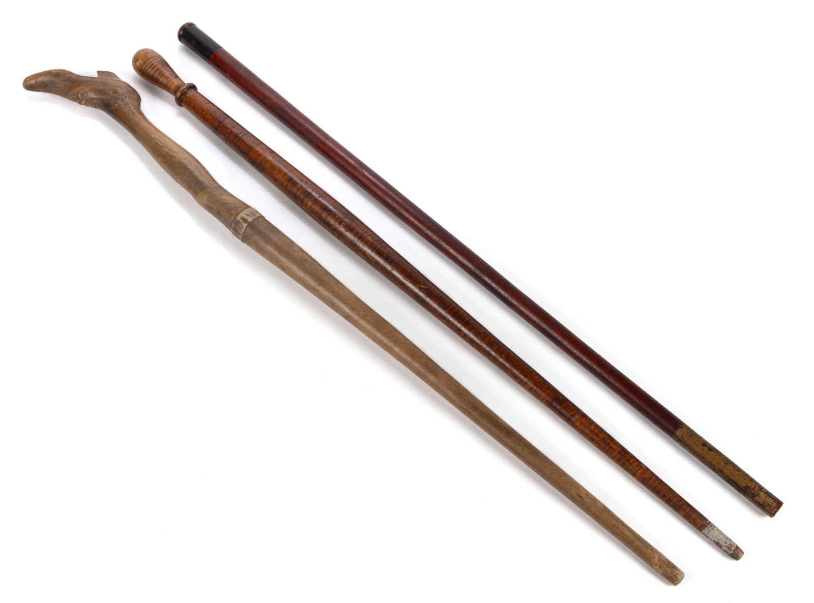 AMERICAN FOLK ART CARVED CANE / WALKING STICK: AMERICAN FOLK ART CARVED CANE / WALKING STICK, probably maple, featuring a lady's leg with shoe for handle, retaining early natural surface. Together with a tiger maple example and a red-painted e