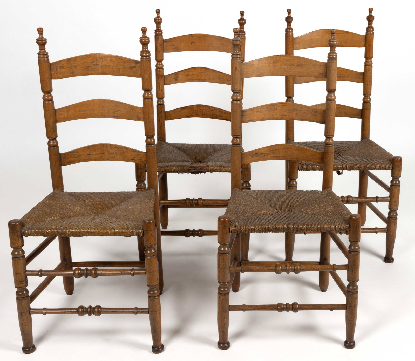 AMERICAN LADDERBACK SIDE CHAIRS, SET OF FOUR: AMERICAN LADDERBACK SIDE CHAIRS, SET OF FOUR, maple, white oak or hickory, each example having turned posts, a three-slat back, and rush seats. Each retains an old finished surface. Probably New 
