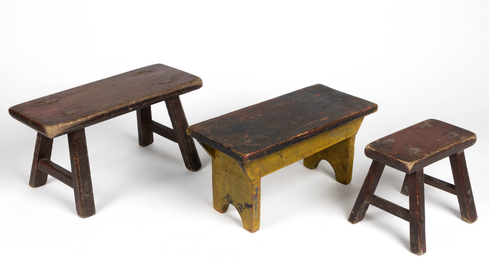 COUNTRY PAINTED FOOTSTOOLS, LOT OF THREE: COUNTRY PAINTED FOOTSTOOLS, LOT OF THREE, two with through-mortised stretchers, one raised on cut-out supports, each retaining an old painted surface. 19th/20th century. 8" H, 7" W, 15 3/4&q