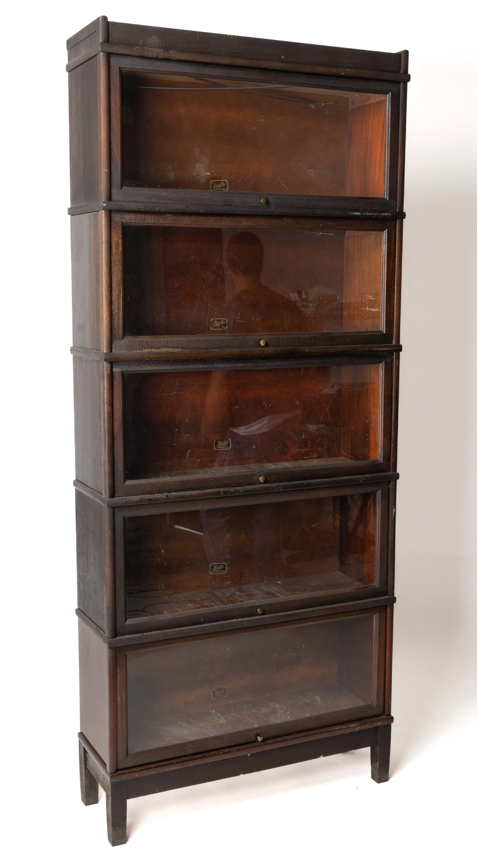 HALE MAHOGANY BARRISTER BOOKCASE: HALE MAHOGANY BARRISTER BOOKCASE, in five stacking sections each section with a fold-up and sliding glass door, all above a base section raised on four square tapered legs. Re