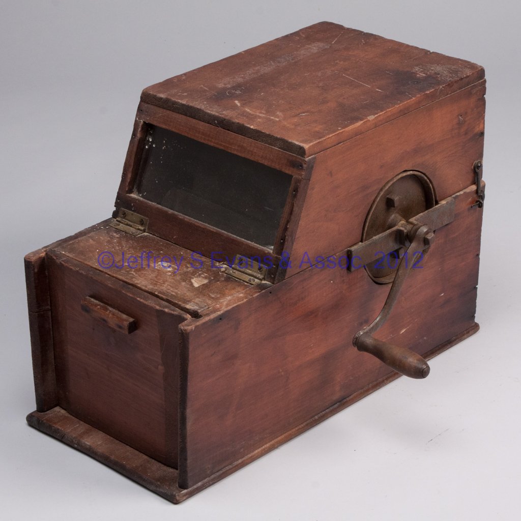 PRIMITIVE ICE CREAM MAKER: PRIMITIVE ICE CREAM MAKER, box form with hinged top and sliding front door, interior metal drum with crank, and two pans, one with wooden roller. Fourth quarter 19th century. 12 1/2" H, 9" x 17 1/2". 