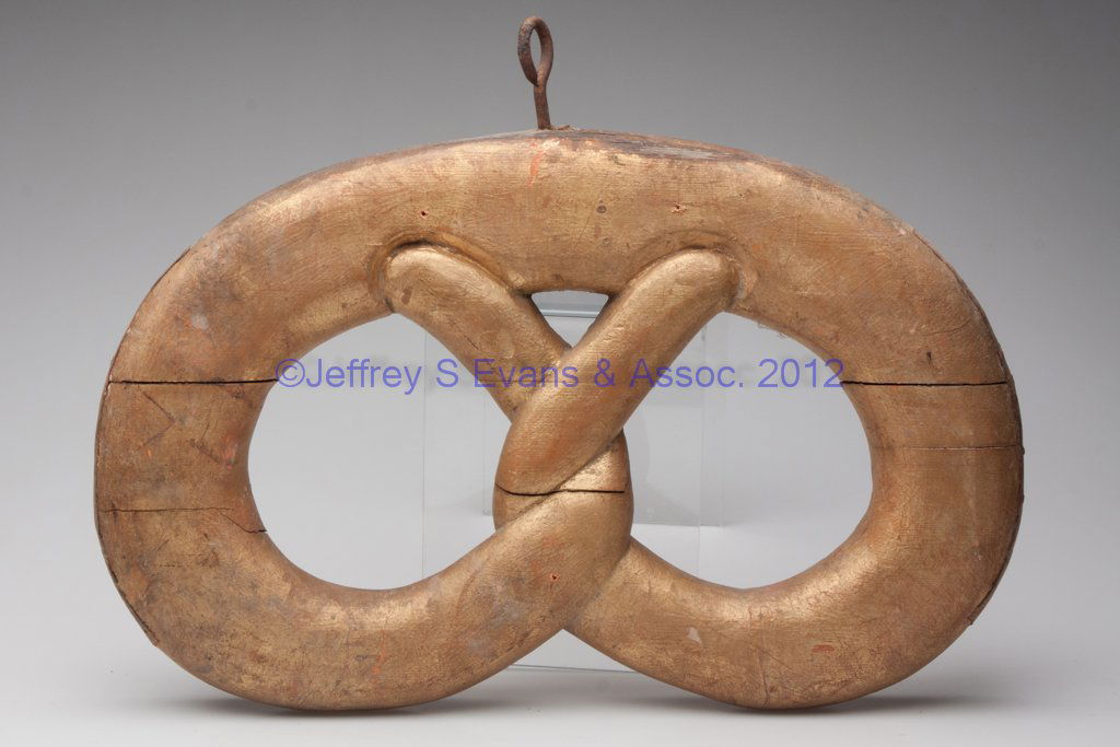 CARVED AND GILDED WOOD PRETZEL TRADE SIGN: CARVED AND GILDED WOOD PRETZEL TRADE SIGN, iron hanging hook in top, tin brace tacked to each outer edge, old repaint. Second half 19th century. 12 1/2" x 19" without hanger. Provenance: The private c