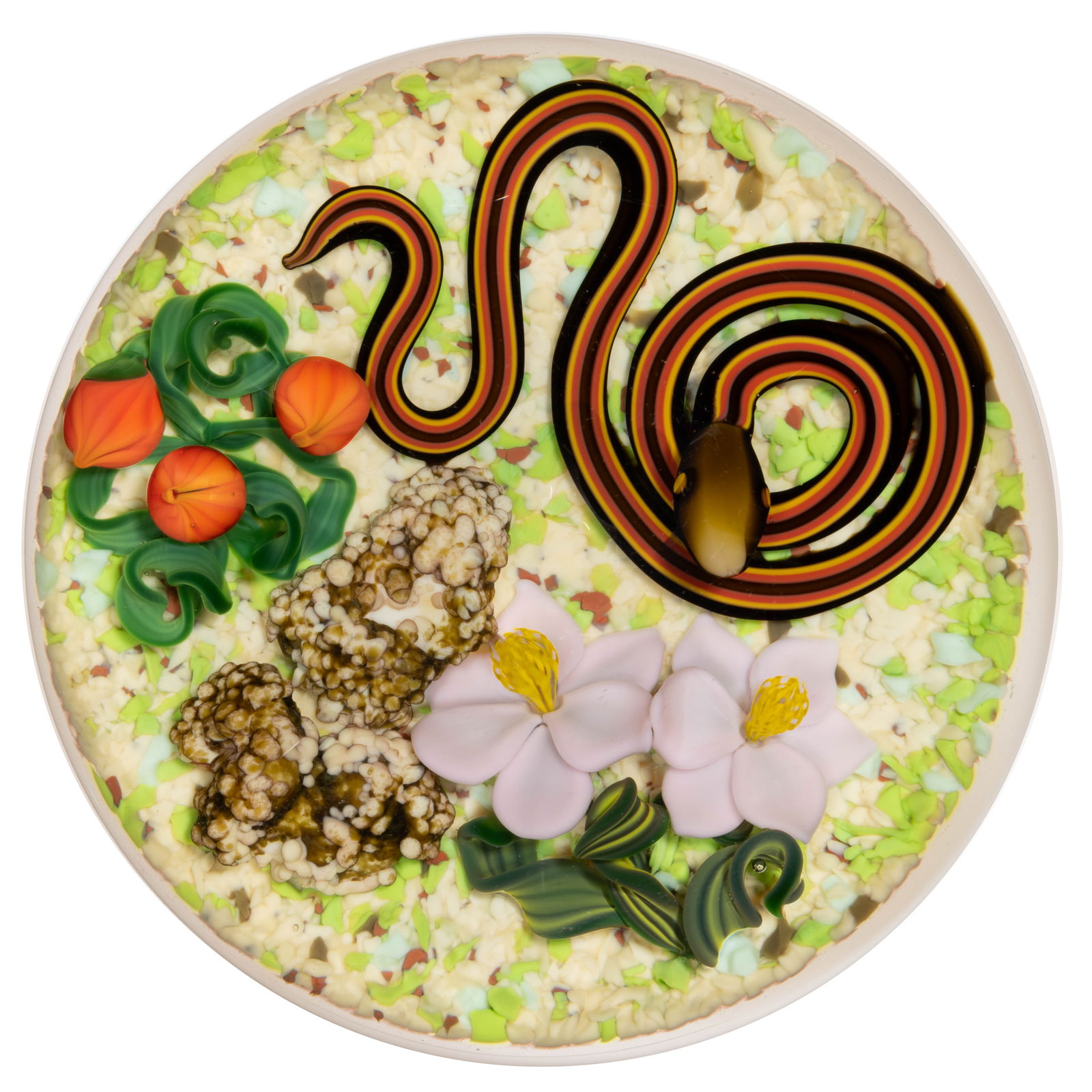GORDON SMITH (AMERICAN, B. 1959) SNAKE IN THE DESERT LAMPWORK STUDIO ART GLASS PAPERWEIGHT: GORDON SMITH (AMERICAN, B. 1959) SNAKE IN THE DESERT LAMPWORK STUDIO ART GLASS PAPERWEIGHT, black, yellow, and orange snake coiled next to two pale pink flower blossoms anchored to variegated green fo