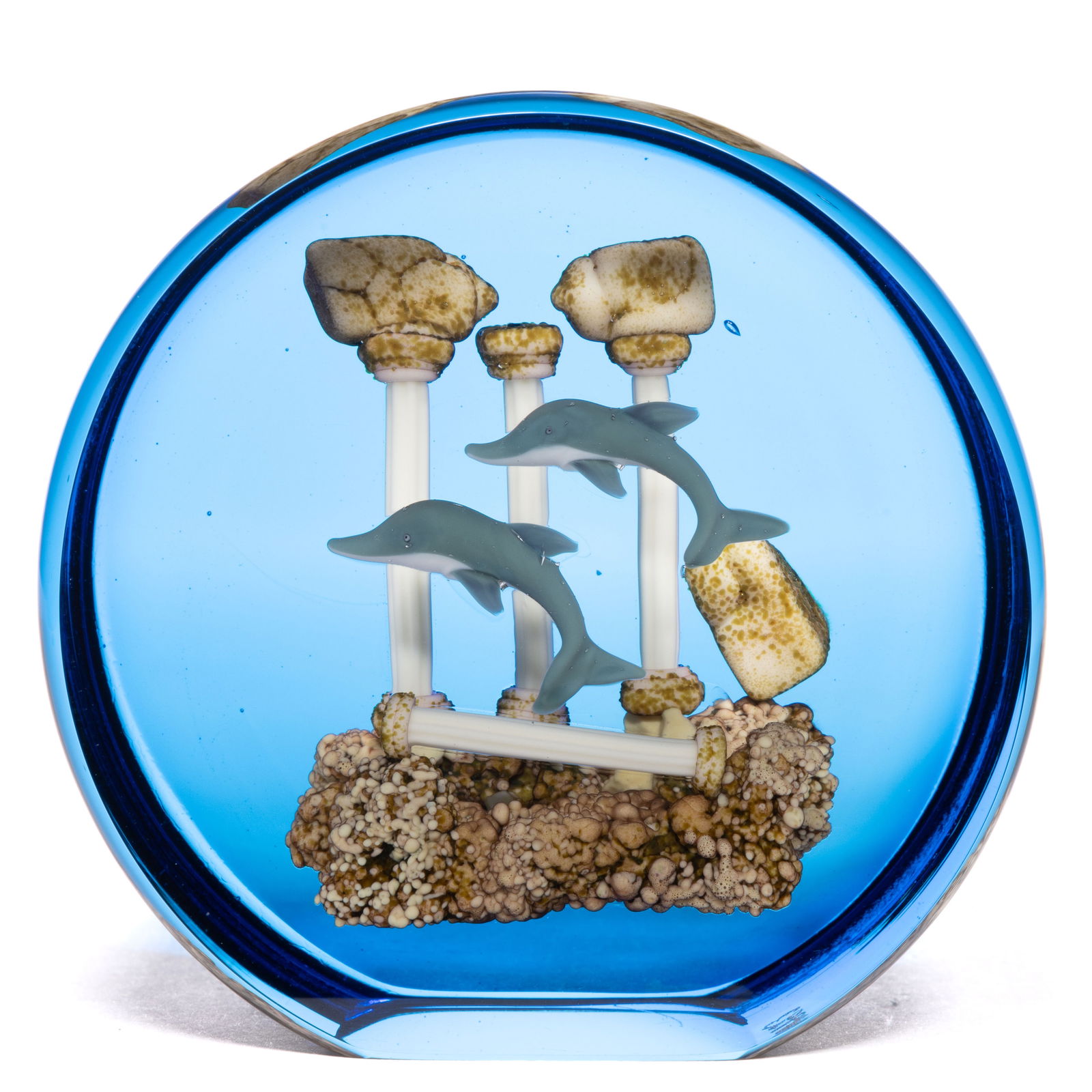 GORDON SMITH (AMERICAN, B. 1959) ATLANTIS LAMPWORK STUDIO ART GLASS UPRIGHT PAPERWEIGHT: GORDON SMITH (AMERICAN, B. 1959) ATLANTIS LAMPWORK STUDIO ART GLASS UPRIGHT PAPERWEIGHT, two blue dolphins swimming above a fallen white Classical column on a brown rocky ground, background featuring