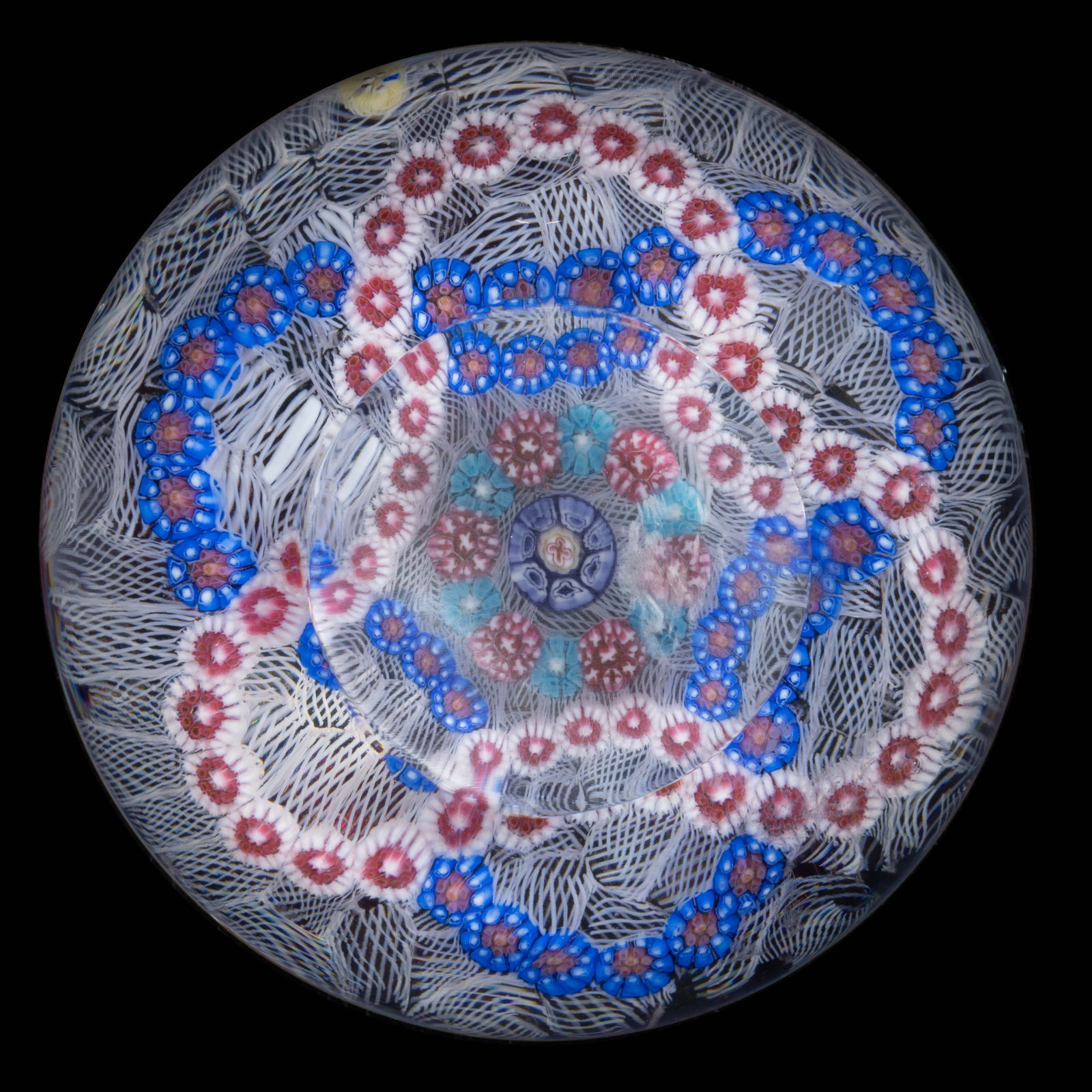 VINTAGE BACCARAT INTERLACED GARLANDS MILLEFIORI ART GLASS PAPERWEIGHT: VINTAGE BACCARAT INTERLACED GARLANDS MILLEFIORI ART GLASS PAPERWEIGHT, cut circular top window, central blue and red cross cane, encircled by an interior garland of alternating blue and white complex