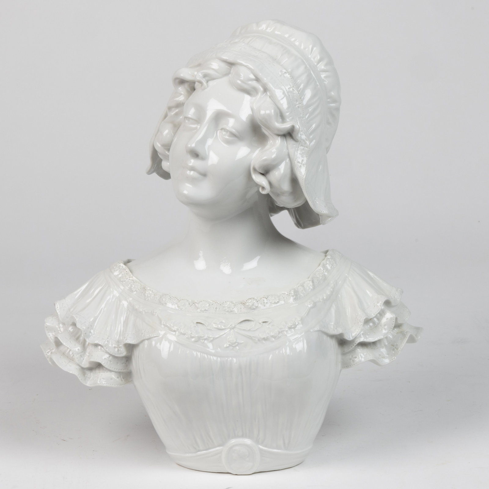 CONTINENTAL PORCELAIN BUST OF A WOMAN: CONTINENTAL PORCELAIN BUST OF A WOMAN, featuring a young woman wearing a cap with a lace-trimmed dress, rippling sleeves, and a cameo belt at her waist. Having "7580" impressed to under