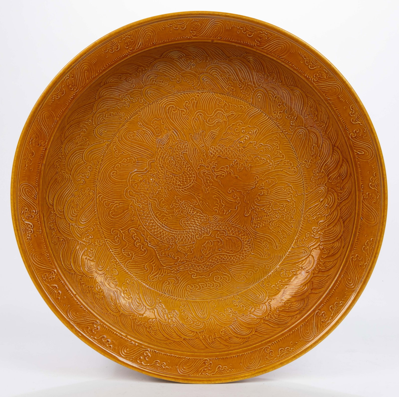 CHINESE EXPORT PORCELAIN DRAGON MOTIF CHARGER: CHINESE EXPORT PORCELAIN DRAGON MOTIF CHARGER, orange-glazed, featuring slightly raised serpentine-bodied reptile amongst waves. Having incised four character mark to underside. Probably 20th/21st cen