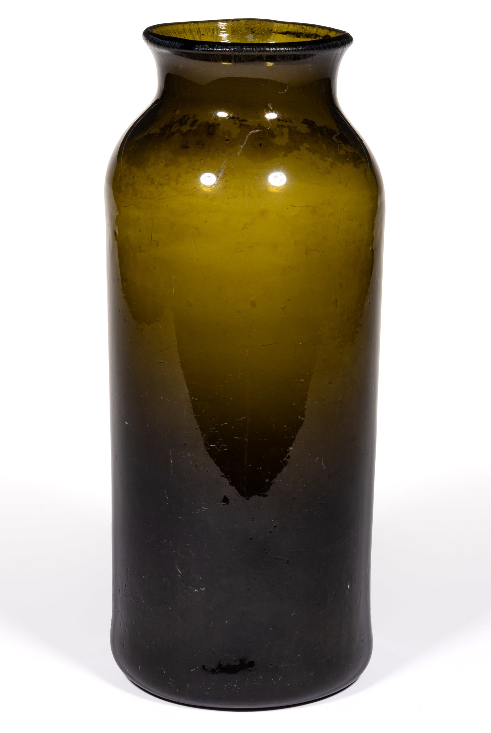 FREE-BLOWN GLASS STORAGE JAR / UTILITY BOTTLE: FREE-BLOWN GLASS STORAGE JAR / UTILITY BOTTLE, dark olive-amber/black glass, tall cylindrical form blown with the aid of a dip mold, slightly-flared wide mouth, kicked-up base with disk pontil scar. P