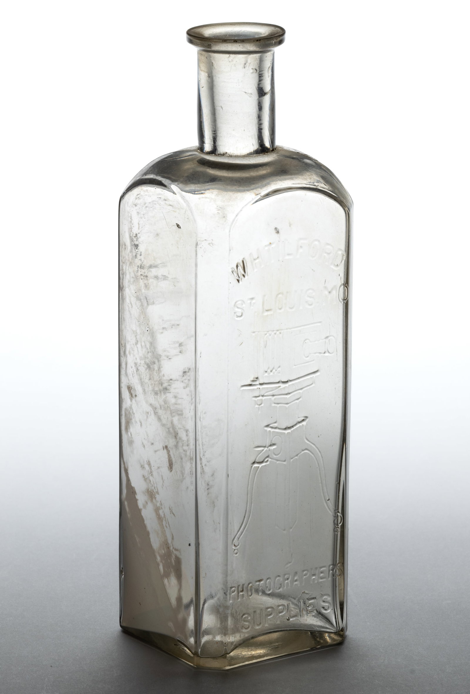 W.H. TILFORD & CO., PICTORIAL PHOTOGRAPHY CHEMICAL / LIQUID DEVELOPER BOTTLE: W.H. TILFORD & CO., PICTORIAL PHOTOGRAPHY CHEMICAL / LIQUID DEVELOPER BOTTLE, colorless, tall square form with flat panels and beveled corners, embossed "W.H. TILFORD / ST. LOUIS. MO" ab