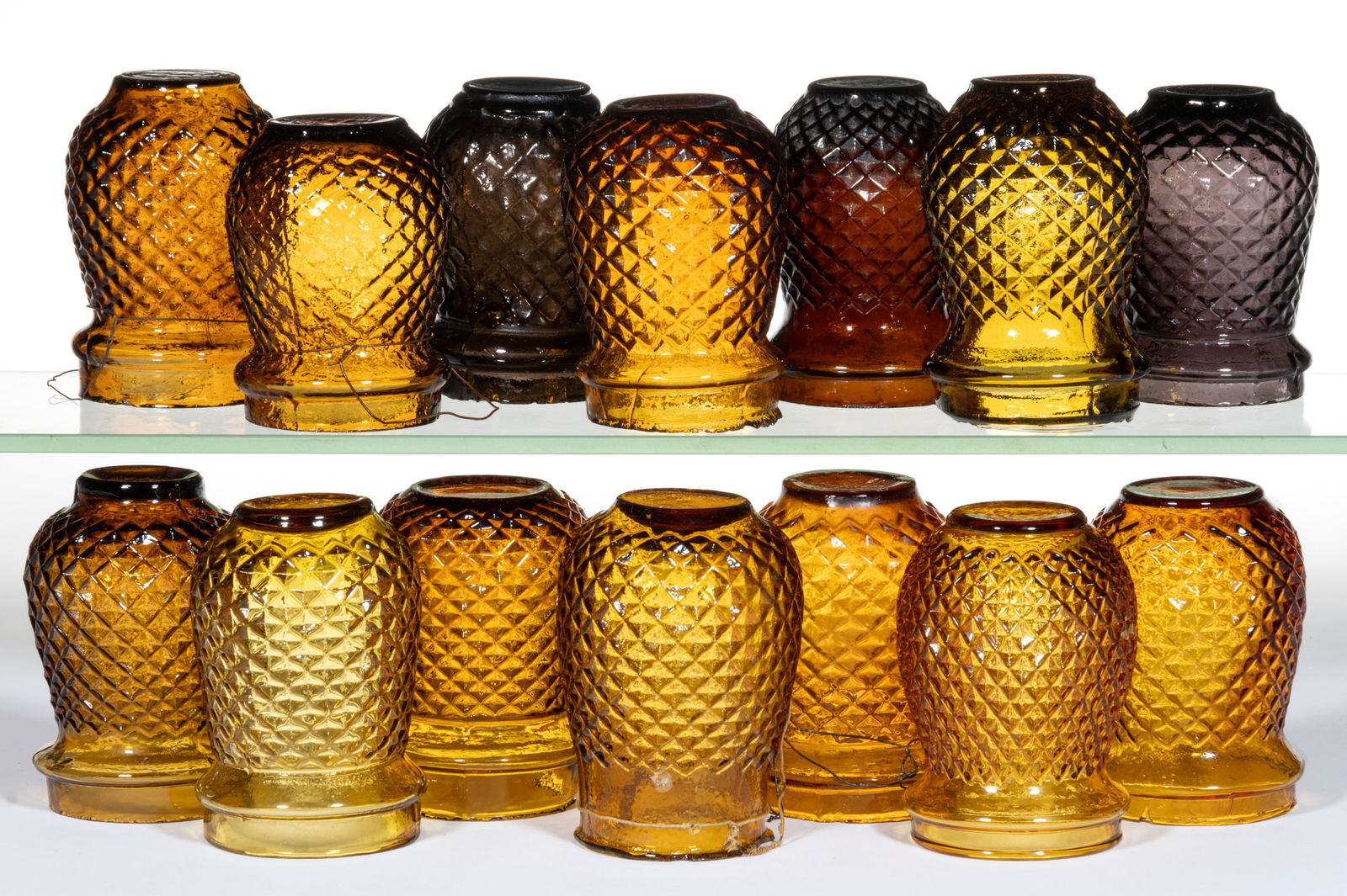 DIAMOND-PATTERN MOLDED GLASS CHRISTMAS LIGHTS, LOT OF 14: DIAMOND-PATTERN MOLDED GLASS CHRISTMAS LIGHTS, LOT OF 14, varying shades of amber or amethyst, including one stamped "BRITISH MADE". Fourth quarter 19th/first quarter 20th century. 3 3/