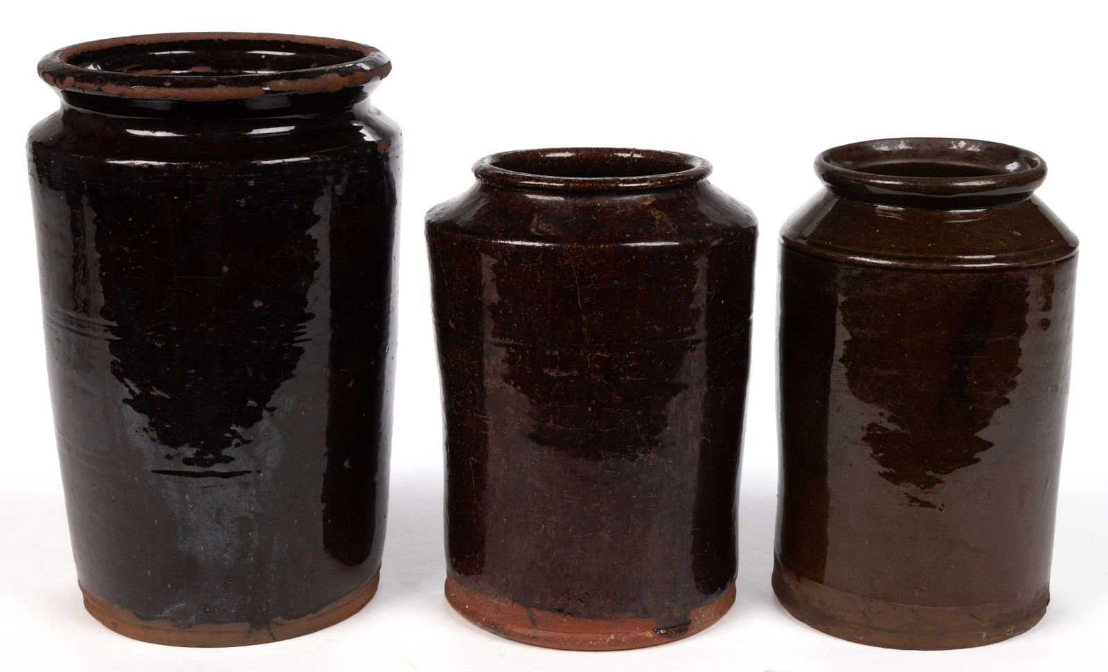 MID-ATLANTIC EARTHENWARE / REDWARE JARS, LOT OF THREE: MID-ATLANTIC EARTHENWARE / REDWARE JARS, LOT OF THREE, lead-glazed to just above foot, each of cylindrical form with sharp shoulder including two with galleried rims. 19th century. 8 1/4" to 10 1