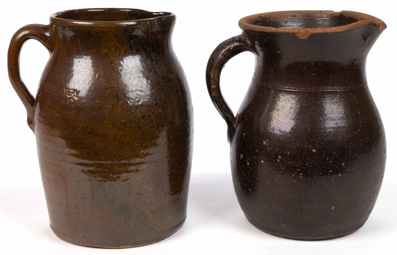 STAMPED GEORGIA AND NORTH CAROLINA EARTHENWARE / REDWARE PITCHERS, LOT OF TWO: STAMPED GEORGIA AND NORTH CAROLINA EARTHENWARE / REDWARE PITCHERS, LOT OF TWO, lead- and manganese-glazed, each approximately one-gallon capacity, comprising one example with "BROWN'