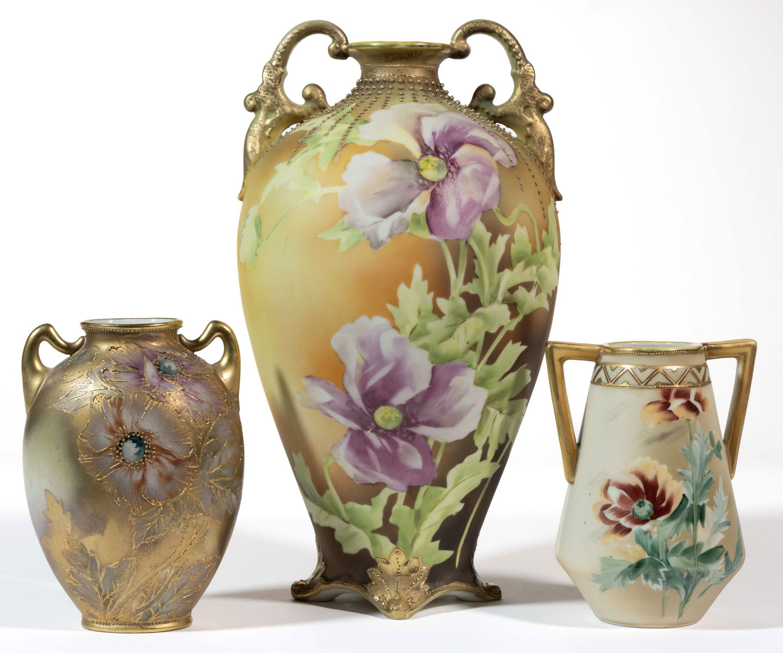 JAPANESE NIPPON PORCELAIN FLORAL MOTIF VASES, LOT OF THREE: JAPANESE NIPPON PORCELAIN FLORAL MOTIF VASES, LOT OF THREE, each having vertical handles and polychrome hand-painted poppy flower designs, comprising one ovoid example with gilt beads emanating from n
