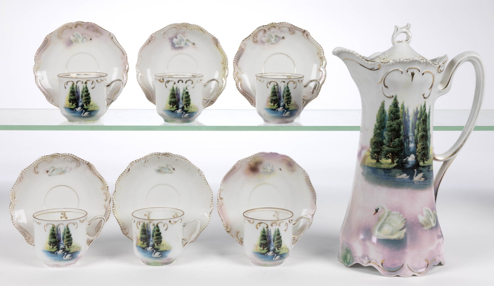 R.S. PRUSSIA PORCELAIN SWAN MOTIF SEVEN-PIECE CHOCOLATE SET: R.S. PRUSSIA PORCELAIN SWAN MOTIF SEVEN-PIECE CHOCOLATE SET, RSP Mold 304, having polychrome transfer scene depicting multiple swans, some floating in stream between large pine trees, having light pin