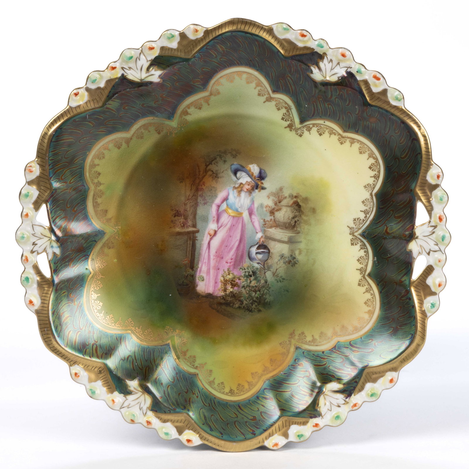 R.S. PRUSSIA PORCELAIN TIFFANY FINISH SCENIC MOTIF CAKE PLATE: R.S. PRUSSIA PORCELAIN TIFFANY FINISH SCENIC MOTIF CAKE PLATE, open-handled having molded leaf and floral bud rim with polychrome transfer depicting a Victorian woman watering flowers to center, and a