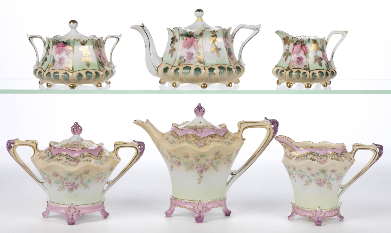 R.S. PRUSSIA PORCELAIN FLORAL MOTIF THREE-PIECE TEA SETS, LOT OF TWO: R.S. PRUSSIA PORCELAIN FLORAL MOTIF THREE-PIECE TEA SETS, LOT OF TWO, each comprising a teapot, a covered sugar, and a creamer with polychrome and gilt transfer images, including one RSP Mold 632 set 