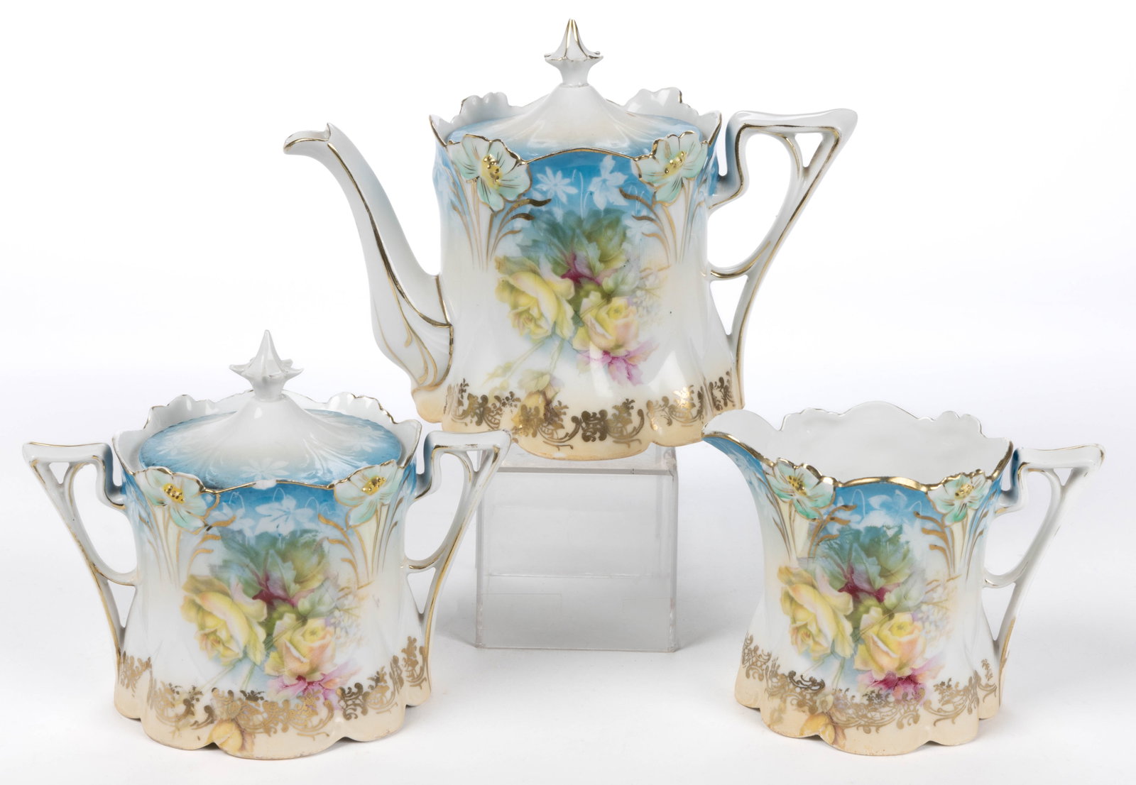 R.S. PRUSSIA PORCELAIN FLORAL MOTIF THREE-PIECE TEA SET: R.S. PRUSSIA PORCELAIN FLORAL MOTIF THREE-PIECE TEA SET, RSP Mold 29, each having molded open flowers to rim, polychrome transfer rose with delicate white flower design, and white shadow flowers on tu