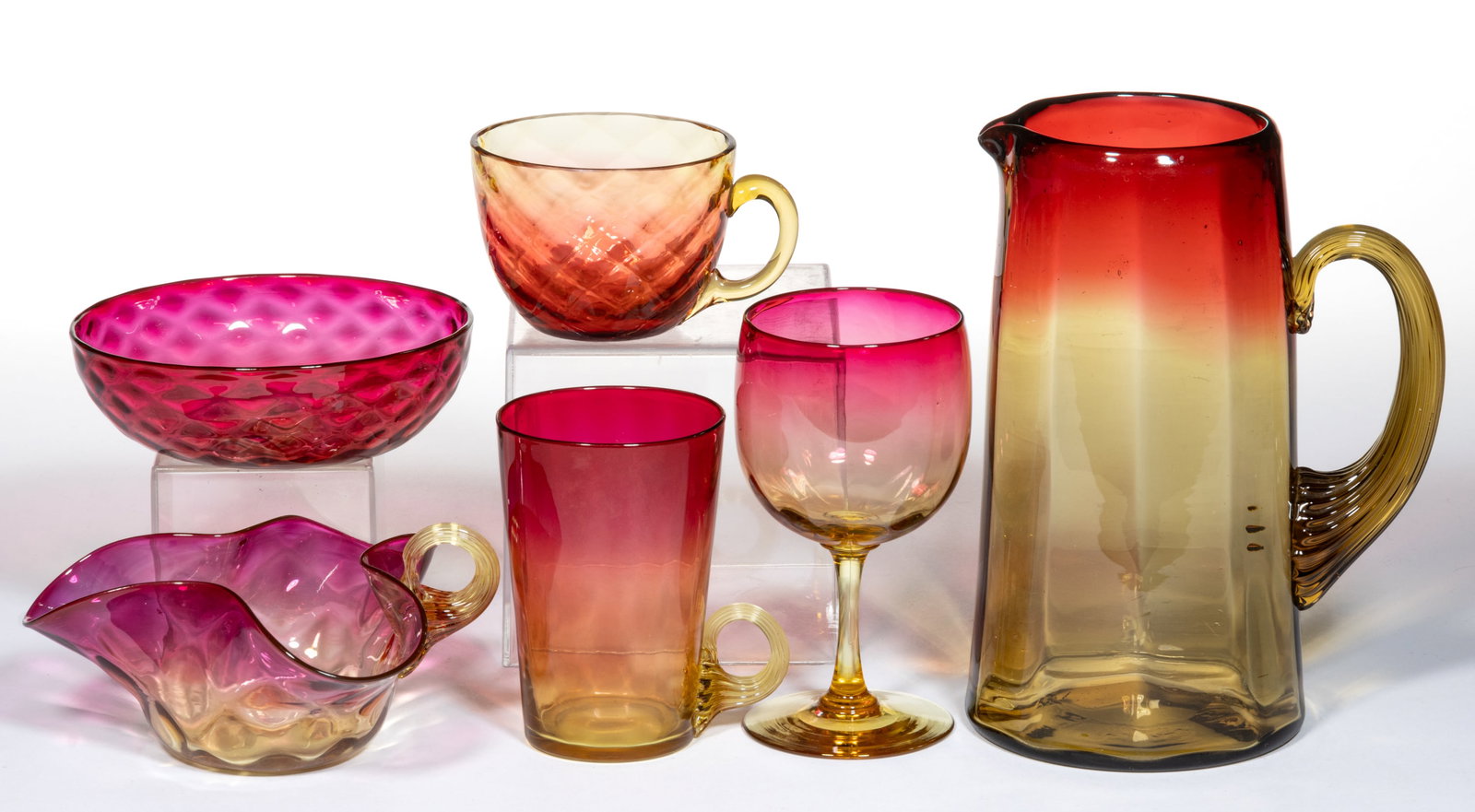 ASSORTED AMBERINA GLASS ARTICLES, LOT OF SIX: ASSORTED AMBERINA GLASS ARTICLES, LOT OF SIX, comprising a Panel-Optic tankard pitcher, a mug with applied amber handle, a wine, a punch cup with a Diamond-Optic pattern, a handled nappy with applied 