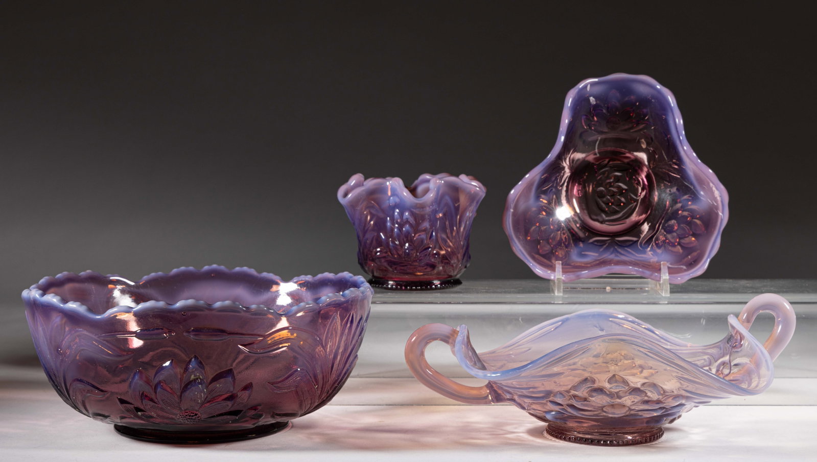 WATERLILY WITH CATTAILS PRESSED OPALESCENT ARTICLES, LOT OF FOUR: WATERLILY WITH CATTAILS PRESSED OPALESCENT ARTICLES, LOT OF FOUR, amethyst opalescent, comprising a master berry bowl, double-handled dish, footed dish, and small vase. Fenton Art Glass Co. Circa 1908