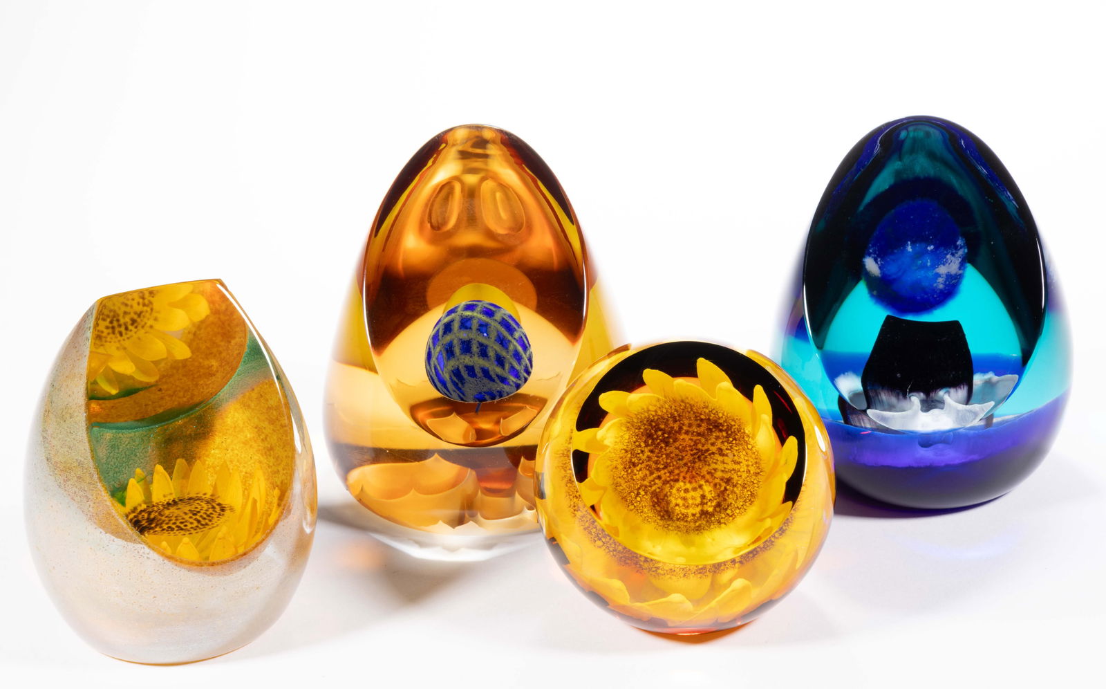VINTAGE CAITHNESS ART GLASS UPRIGHT PAPERWEIGHTS, LOT OF FOUR: VINTAGE CAITHNESS ART GLASS UPRIGHT PAPERWEIGHTS, LOT OF FOUR, comprising a "Sunflower", a "Sunseeker", a "Lunar Enigma", and one unsigned but having a blue sphere in the center and an etched base. Sc