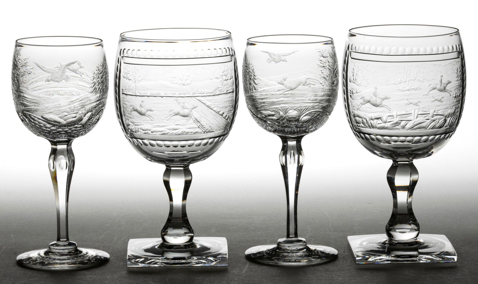 SIGNED WEBB INTAGLIO CUT LANDSCAPES ROCK CRYSTAL STEMWARE, LOT OF FOUR: SIGNED WEBB INTAGLIO CUT LANDSCAPES ROCK CRYSTAL STEMWARE, LOT OF FOUR, colorless, comprising a pair of goblets, each bowl having a rectangular reserve featuring a different fox hunting scene, raised