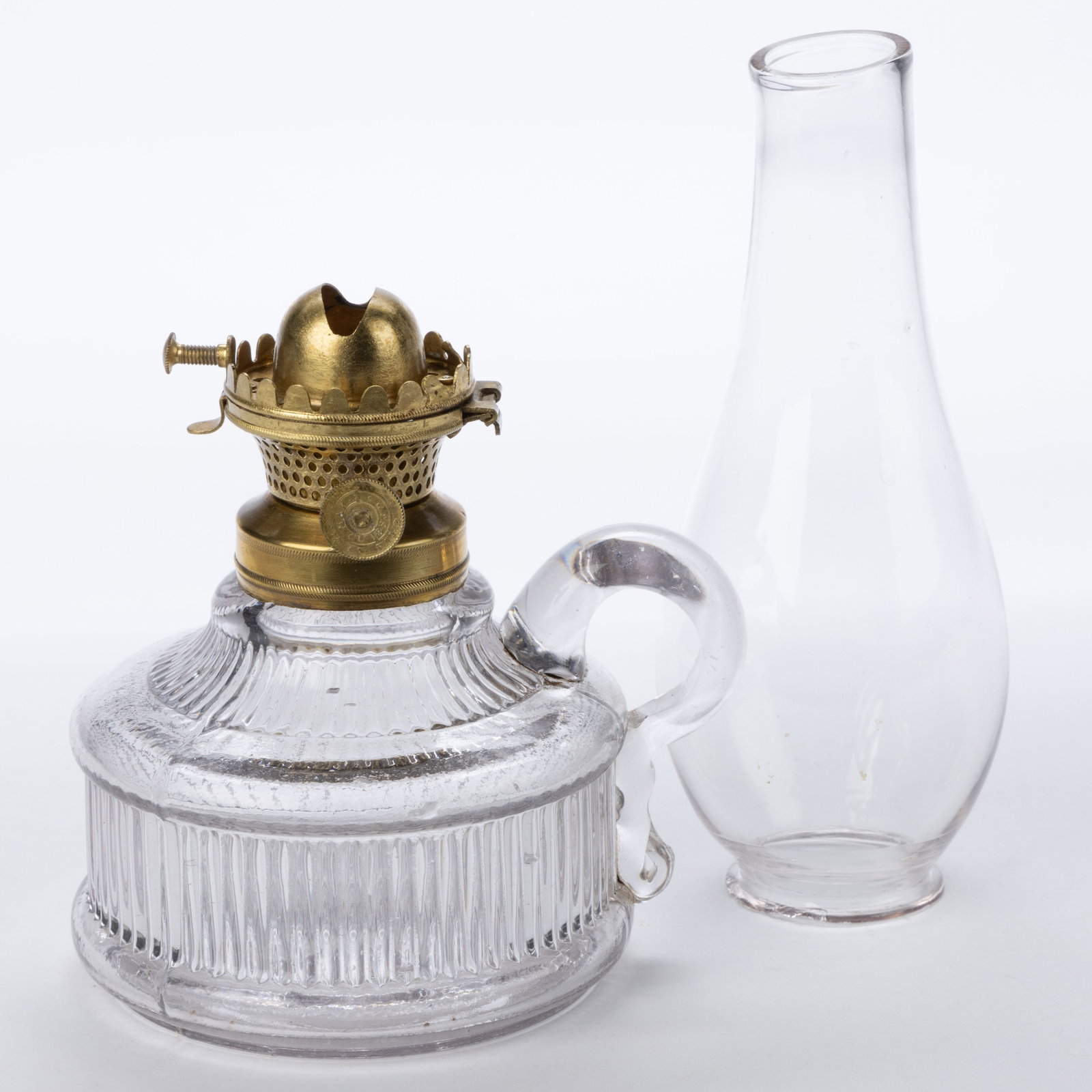 CITY MANUFACTURING CO. NO. 0 HINGED LIP BURNER AND CHIMNEY SETUP: CITY MANUFACTURING CO. NO. 0 HINGED LIP BURNER AND CHIMNEY SETUP, brass burner, thumbwheel marked "CITY M. F. G. CO. / PAT'D MAR. 3 / 1863", hinged deflector, colorless lip chimney. Fitted on a colorl