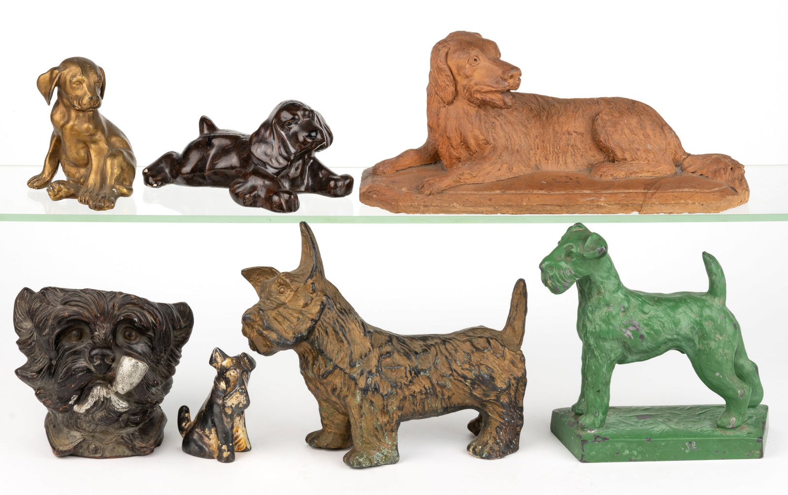 ASSORTED CAST-METAL AND CERAMIC DOG FIGURES / ARTICLES, LOT OF SEVEN: ASSORTED CAST-METAL AND CERAMIC DOG FIGURES / ARTICLES, LOT OF SEVEN, including a redware recumbent dog on a platform base; a German Scottie humidor; and a single cast-metal Scottie shaker. Late 19th/