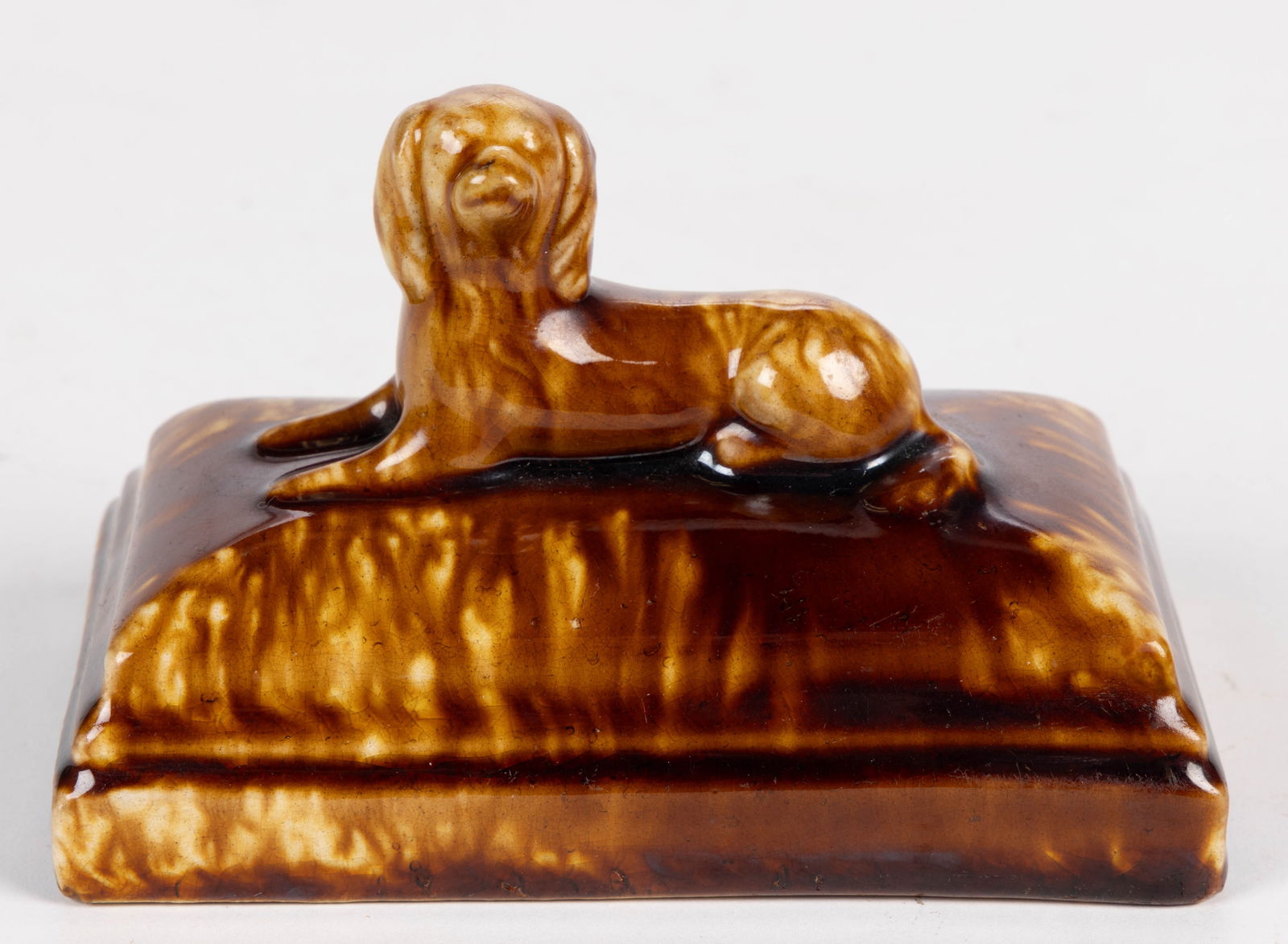 BENNINGTON ATTRIBUTED ROCKINGHAM-GLAZED POTTERY FIGURAL DOG / SPANIEL PAPERWEIGHT: BENNINGTON ATTRIBUTED ROCKINGHAM-GLAZED POTTERY FIGURAL DOG / SPANIEL PAPERWEIGHT, mottled/streaky brown glaze over solid buff earthenware body, molded in the form of a left-facing long-hair
