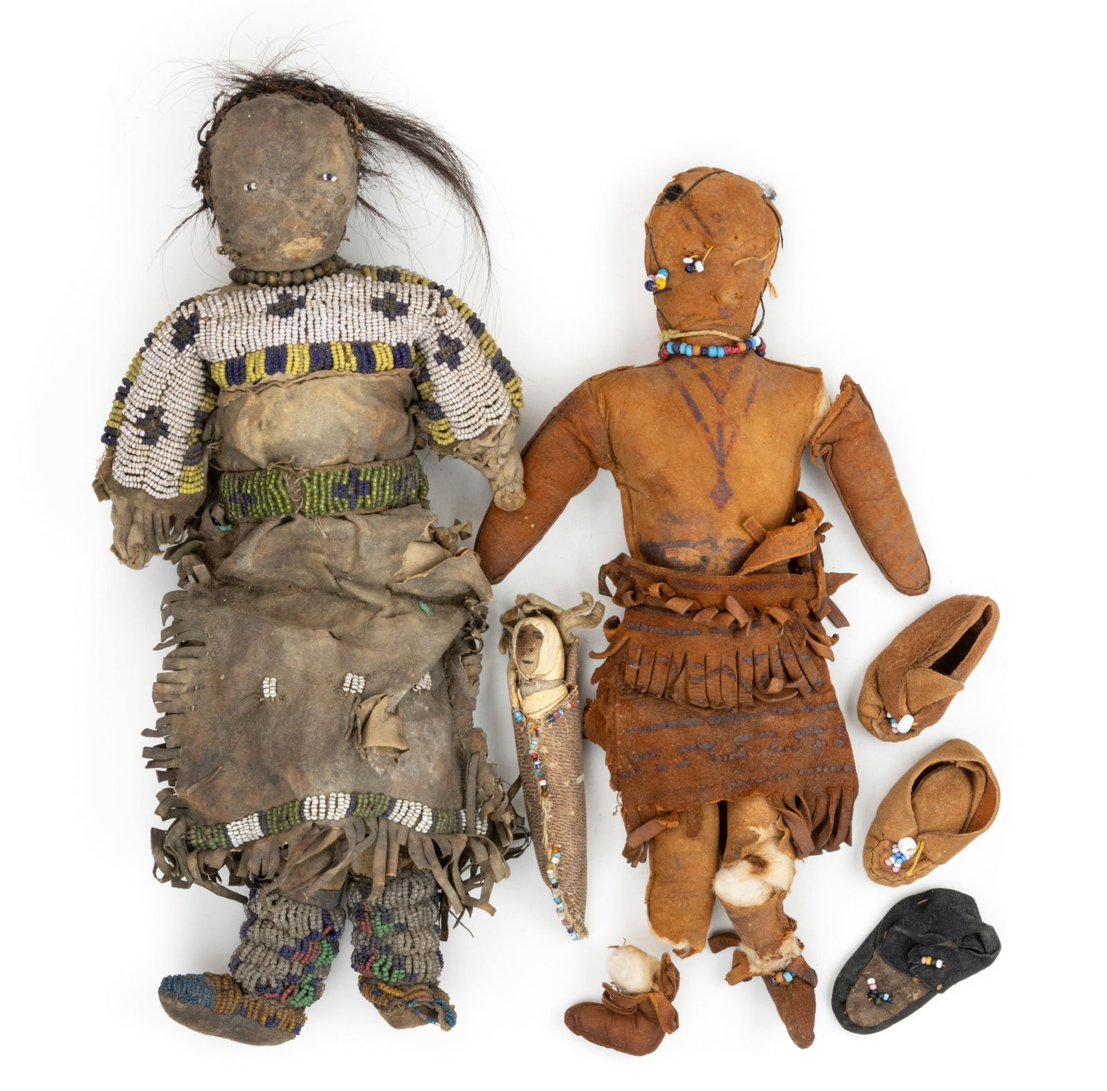 ASSORTED SKOOKUM-TYPE / NATIVE AMERICAN CLOTH DOLLS AND CLOTHING, UNCOUNTED LOT: ASSORTED SKOOKUM-TYPE / NATIVE AMERICAN CLOTH DOLLS AND CLOTHING, UNCOUNTED LOT, comprising of two large dolls and a miniature infant papoose, each with beaded facial features, one example with hair,