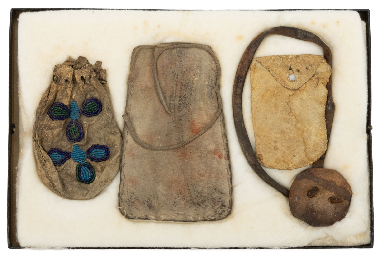 NATIVE AMERICAN HIDE / LEATHER BAGS AND BAND, LOT OF FOUR: NATIVE AMERICAN HIDE / LEATHER BAGS AND BAND, LOT OF FOUR, comprising a Plains Indian, possibly Lakota, small bag with beaded decoration to one side, a bag with leather tie attached to side, a small r