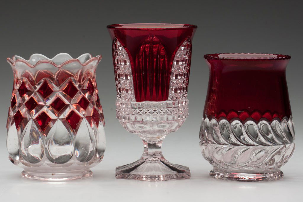 RUBY-STAINED EAPG SPOONERS, LOT OF THREE: RUBY-STAINED EAPG SPOONERS, LOT OF THREE, colorless, comprising Art, Cathedral and Plume examples. Fourth quarter 19th century. 4 3/4" to 5 5/8" H. Provenance: The collection of the late Cora H. Teter