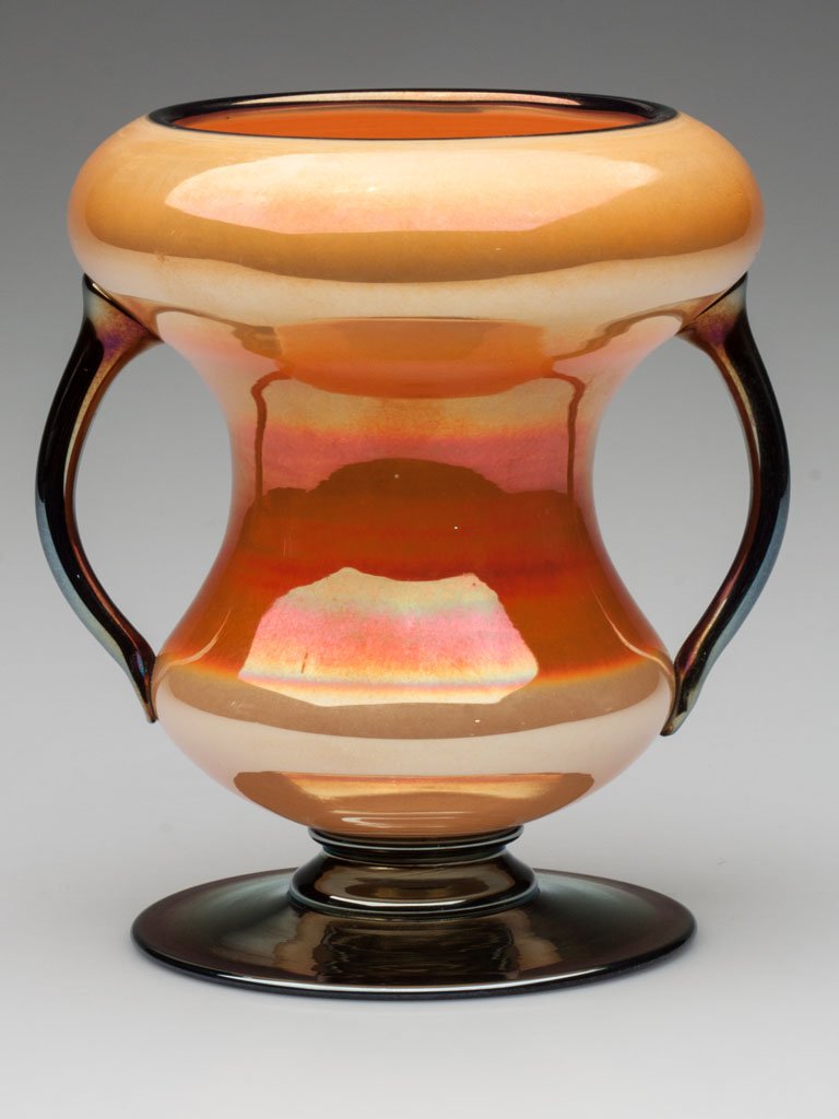 IMPERIAL FREE HAND VASE: IMPERIAL FREE HAND VASE, glossy iridescent orange with blue rim, applied blue upright open handles and broad foot, shape as catalogue number FH 228, polished pontil mark. Imperial Glass Co. Circa 1925