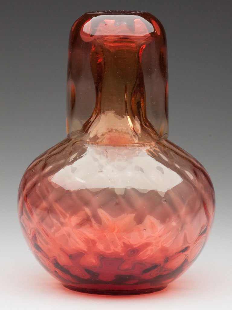AMBERINA-REVERSE OPTIC TUMBLE-UP: AMBERINA-REVERSE OPTIC TUMBLE-UP, comprising a diamond-optic bottle with polished pontil mark and a spot-optic tumbler, together by association. Fourth quarter 19th century. 8" H. Provenance: Jerry Ly