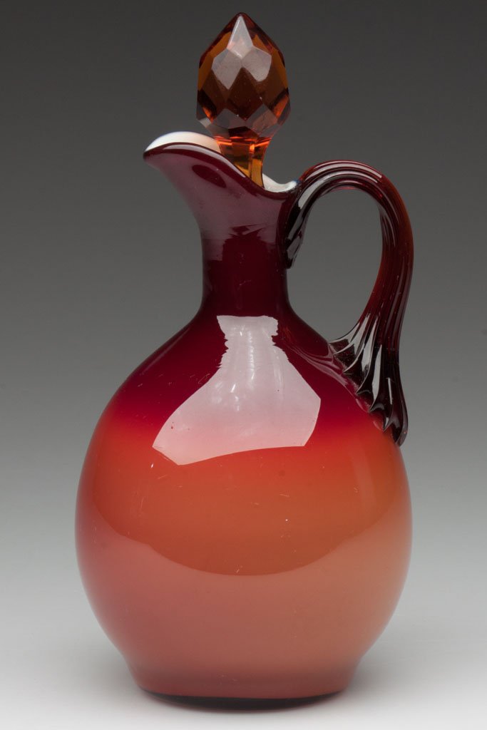 HOBBS DARK CORAL / PEACH BLOW NO. 312 CRUET: HOBBS DARK CORAL / PEACH BLOW NO. 312 CRUET, dark amber applied reeded handle and faceted stopper, polished pontil mark. Hobbs, Brockunier & Co. Fourth quarter 19th century. 7" HOA. Literature: Bredeh