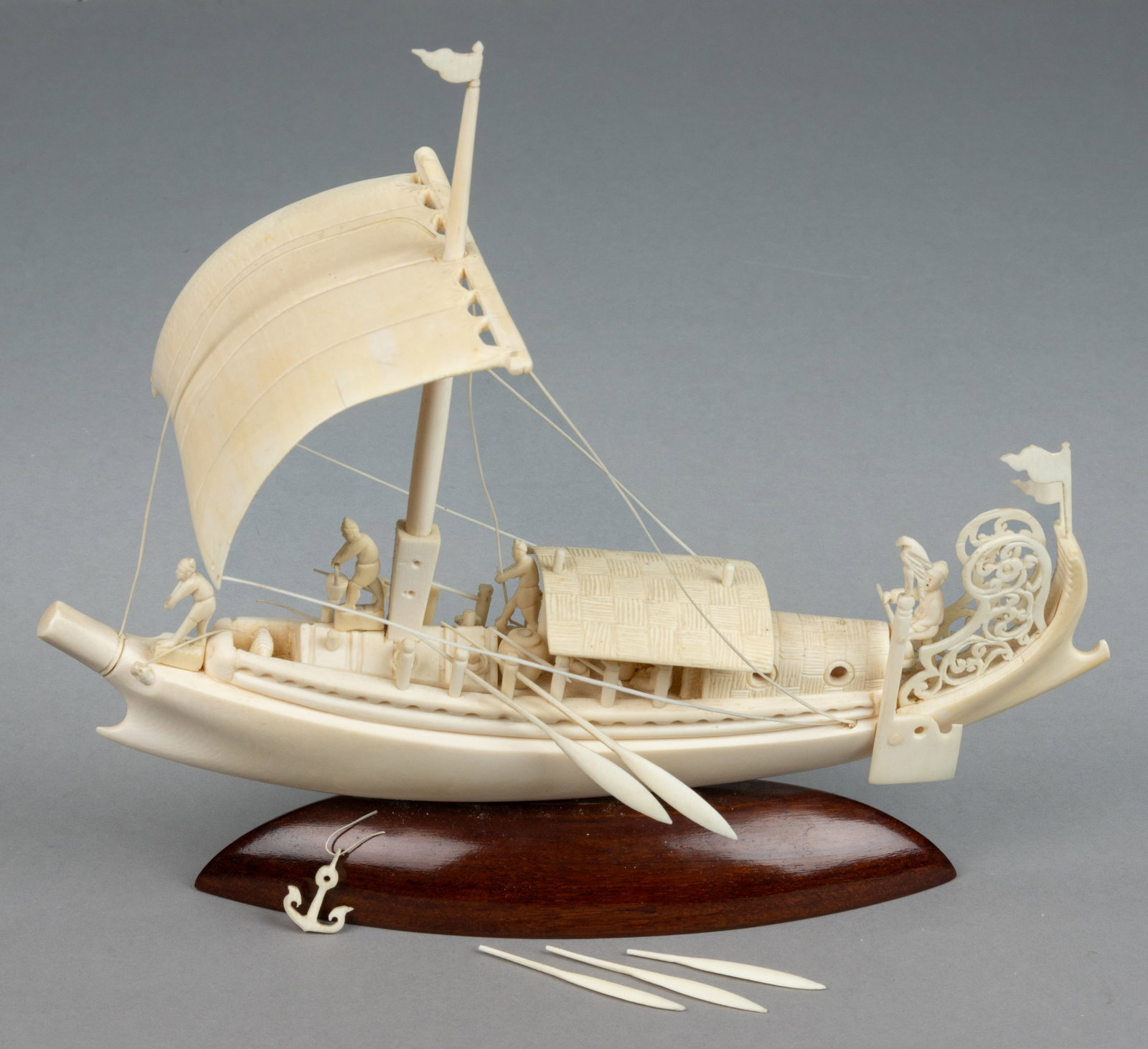 CHINESE CARVED BONE SHIP / SAIL BOAT: CHINESE CARVED BONE SHIP / SAIL BOAT, constructed from intricately carved bone, depicting a single-sailed vessel with a number of crew members preforming various tasks on board, the whole connects to